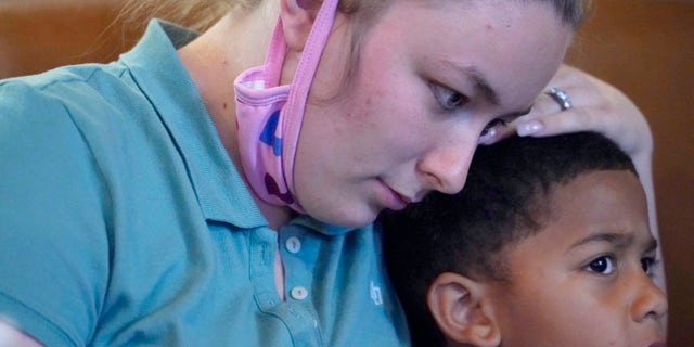 Alexis Rankin, hugs her oldest son, Peyton Lee, 5, as she recalls the events of the evening of February 8, 2018, when she and her on-again-off-again boyfriend Willie Jones Jr., argued while on their way to her stepfather's home in Scott County, Miss. Shortly after arriving, Jones, who is black, was discovered hanging from a tree in the yard of Rankin's family home. The sheriff's department and the Mississippi Bureau of Investigation, both ruled the death a suicide. However, a Jackson-area judge in April awarded close to $11.4 million to Jones' family in a civil suit claiming wrongful death, alleging that Rankin's stepfather, Harold O'Bryant, Jr., either killed Jones or failed to prevent him from killing himself. (AP Photo/Rogelio V. Solis)