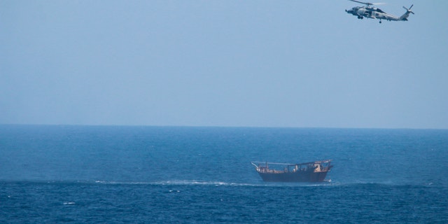 A U.S. Navy Seahawk helicopter flies over a stateless dhow later found to be carrying a hidden arms shipment in the Arabian Sea on Thursday, May 6, 2021. The U.S. Navy announced Sunday it seized the arms shipment hidden aboard the vessel in the Arabian Sea, the latest-such interdiction by sailors amid the long-running war in Yemen. (U.S. Navy via AP)