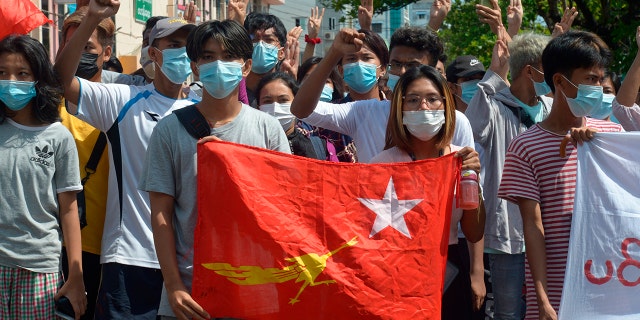 Anti-coup protesters hold the flag of the National League for Democracy party of ousted Myanmar leader Aung San Suu Kyi, while others flash the three-fingered salute during a "flash mob" rally in Bahan township in Yangon, Myanmar, Sunday, May 9, 2021. (AP Photo)