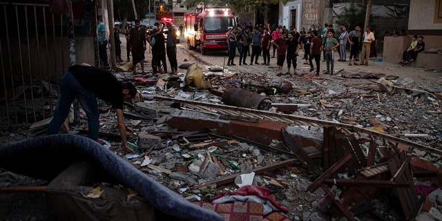 A Palestinian man inspects the rubble of a partially destroyed residential building after it was hit by Israeli missile strikes, at the Shati refugee camp in Gaza City, early Tuesday, May. 11, 2021. (AP Photo/Khalil Hamra)