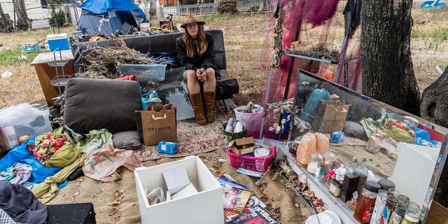 Dawn Woodward, 39, who is homeless and originally from Arizona, sits outdoors in a homeless camp on the side of the CA-101 highway in Echo Park neighborhood in Los Angeles. (AP Photo/Damian Dovarganes)