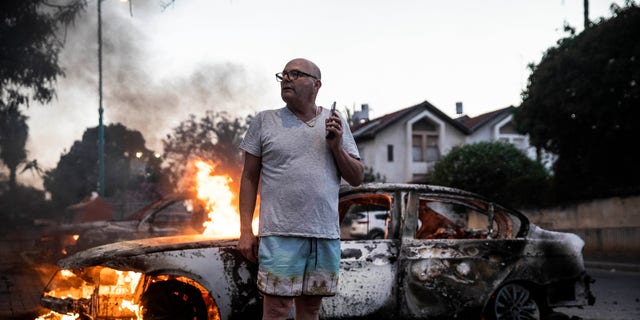 Jacob Simona stands by his burning car during clashes with Israeli Arabs and police in the Israeli mixed city of Lod, Israel Tuesday, May 11,2021. (AP Photo/Heidi Levine)