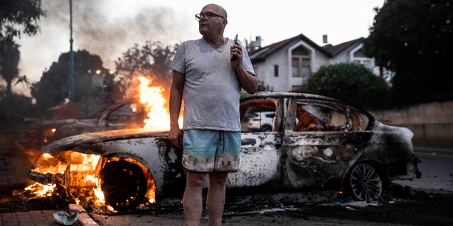 Jacob Simona stands by his burning car during clashes with Israeli Arabs and police in the Israeli mixed city of Lod, Israel Tuesday, May 11,2021. (AP Photo/Heidi Levine)