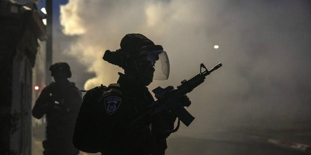 Israeli forces run during clashes with Israeli Arabs in the Israeli mixed city of Lod, Israel, Tuesday, May 11,2021. (AP Photo/Heidi Levine)