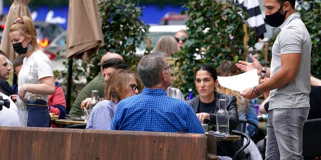 FILE: Patrons at a sidewalk cafe are seated without masks in Boston.