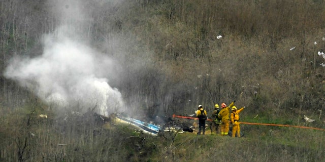 Firefighters work the scene of a helicopter crash where former NBA basketball star Kobe Bryant died, in Calabasas, Calif. His widow, Vanessa Bryant, is suing the county after deputies shared gruesome photos of the basketball great's remains.