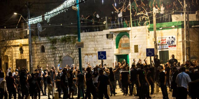 Israeli Arabs gather next to a mosque during clashes between Jews, Israeli police and Arabs, in the mixed town of Lod, central Israel, Wednesday, May 12, 2021.