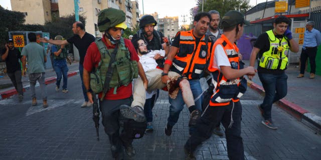 Israeli security forces and paramedics carry a wounded Jewish man after he was shot during violent unrest in Lod, Israel, Thursday, May 13, 2021.