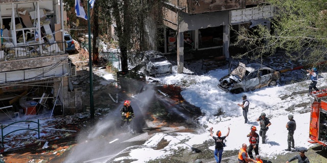 Israeli security forces and emergency services work on a site hit by a rocket fired from the Gaza Strip, in Ramat Gan, central Israel, 星期六, 可能 15, 2021. (AP Photo/Oded Balilty)