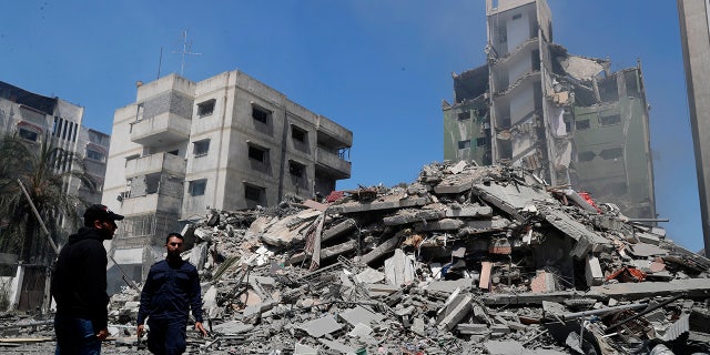 Hamas police officer stands guard amid the rubble of the Yazegi residential building that was destroyed by an Israeli airstrike, in Gaza City, Sunday, May 16, 2021. (AP Photo/Adel Hana)