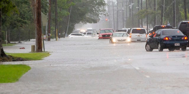 Cars sit stalled on a flooded McNeese Street during heavy rains in Lake Charles, La., Monday, May 17, 2021. (Rick Hickman/American Press via AP)