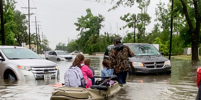 Parents use boats to pick up students from schools after nearly a foot of rain fell in Lake Charles, La., Monday, May 17, 2021. (Rick Hickman/American Press via AP)