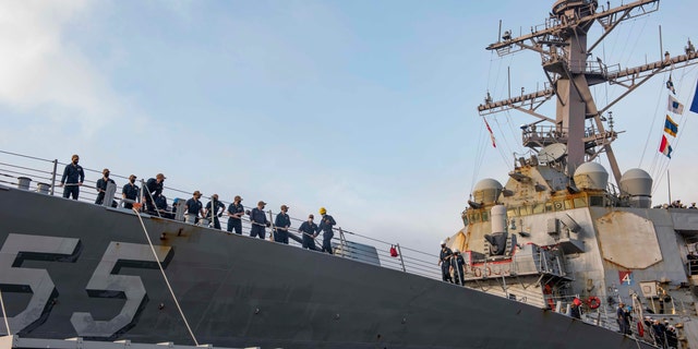 In this photo provided by the U.S. Navy, sailors aboard the guided missile destroyer USS Stout handle mooring lines during the ship's return to home port at Naval Station Norfolk, in Norfolk, Va., in this Oct. 12, 2020, photo. The USS Stout showed rust as it returned from the 210-day deployment. The rust was quickly removed and the ship repainted. But the rusty ship and its weary crew underscored the costly toll of deferred maintenance on ships and long deployments on sailors. (Spc. Jason Pastrick/U.S. Navy via AP)