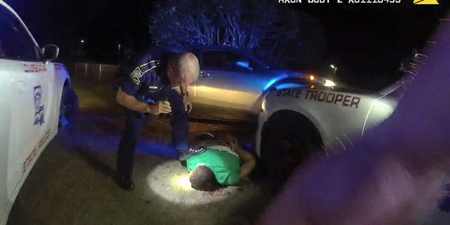 This image from video from Louisiana state police state trooper Dakota DeMoss' body-worn camera, shows trooper Kory York bending over with his foot on Ronald Greene's shoulder after he was taken into custody on May 10, 2019, outside of Monroe, La. The video obtained by The Associated Press shows Louisiana state troopers stunning, punching and dragging the Black man as he apologizes for leading them on a high-speed chase, footage authorities refused to release in the two years since Greene died in police custody. (Louisiana State Police via AP)