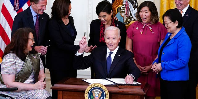 President Joe Biden hands out a pen after signing the COVID-19 Hate Crimes Act, in the East Room of the White House, Thursday, May 20, 2021, in Washington. Clockwise from left, Sen. Tammy Duckworth, R-Ill., Sen. Richard Blumenthal, D-Conn., Vice President Kamala Harris, Rep. Judy Chu, D-Calif., Rep. Grace Meng, D-N.Y., Rep. Don Beyer, D-Va., and Sen. Mazie Hirono, D-Hawaii. (AP Photo/Evan Vucci)