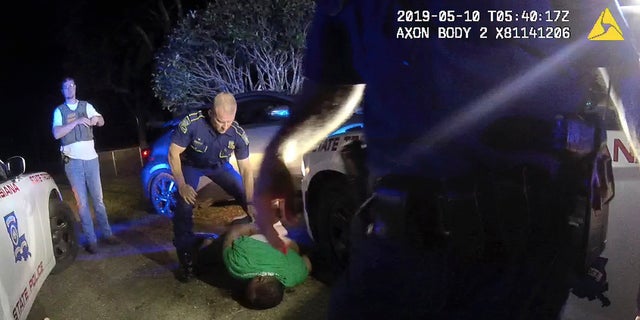 Officers standing over Greene as he lay in the dirt