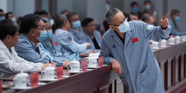 In this photo released by China's Xinhua News Agency, Zhang Rongqiao, right, the chief designer of China's Mars exploration mission, talks with Wu Weiren, second from left, the chief designer of China's lunar exploration project, at the Beijing Aerospace Control Center in Beijing, Saturday, May 22, 2021. China's first Mars rover has driven down from its landing platform and is now roaming the surface of the red planet, China's space administration said Saturday. (Jin Liwang/Xinhua via AP)