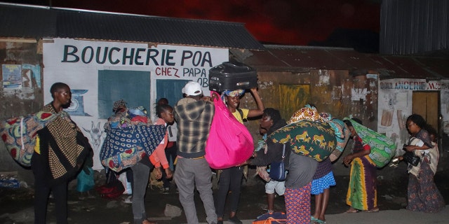 People flee with their belongings after the eruption of Mount Nyiragongo, in Goma, Congo, Saturday, May 22, 2021. Congo's Mount Nyiragongo erupted for the first time in nearly two decades Saturday, turning the night sky a fiery red and sending lava onto a major highway as panicked residents tried to flee Goma, a city of nearly 2 million. (AP Photo/Justin Kabumba)