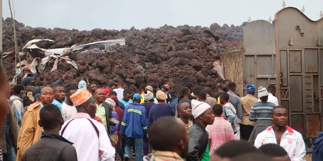 Os moradores estão revisando os danos causados ​​pela lava da erupção noturna do Monte Nyiragongo em Buhene, nos arredores de Goma, no Congo, na madrugada de 23 de maio de 2021.  O Monte Nyiragongo, no Congo, entrou em erupção no sábado pela primeira vez em quase duas décadas.  Tinja o céu noturno de um vermelho intenso e envie lava em uma grande rodovia quando moradores em pânico tentam fugir de Goma, uma cidade de quase 2 milhões de habitantes.  (AP Photo / Justin Kabumba)