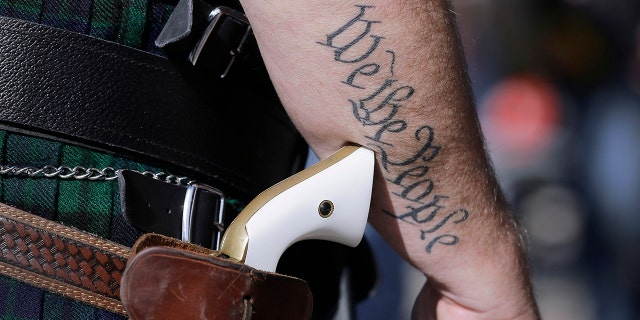 In this Jan. 26, 2015 file photo, a supporter of open carry gun laws, wears a pistol as he prepares for a rally in support of open carry gun laws at the Capitol, in Austin, Texas. (AP Photo/Eric Gay, File)