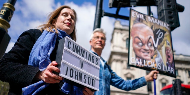 Protesters hold placards near Parliament Square, in London, on the day Dominic Cummings, the volatile advisor who until late last year was British Prime Minister Boris Johnson's most powerful and trusted aide, attended a select committee hearing at Portcullis House nearby, Wednesday, May 26, 2021. In recent days, Cummings has directed a torrent of criticism at Johnson's Conservative government in an ever-lengthening string of Twitter posts. On Wednesday, he plans to make the claims in person, testifying on live television to lawmakers investigating Britain's handling of COVID-19. (AP Photo/Alberto Pezzali)