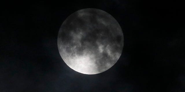 The lunar eclipse progress is seen behind the clouds over Santa Monica Beach in Santa Monica, Calif., Wednesday, May 26, 2021. The first total lunar eclipse in more than two years is coinciding with a supermoon for quite a cosmic show. (AP Photo/Ringo H.W. Chiu)