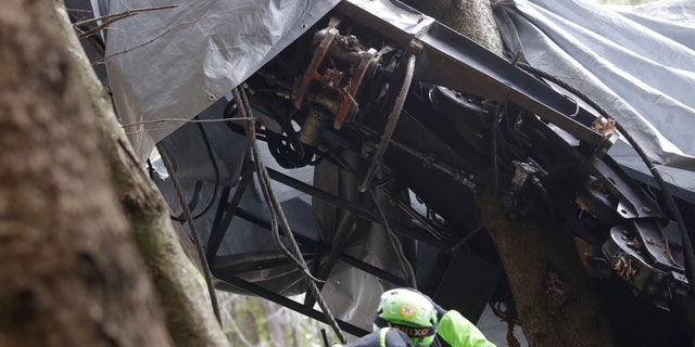 A rescuer takes a picture of a clamp that was placed on an emergency brake, as search for evidence continues in the wreckage of a cable car after it collapsed near the summit of the Stresa-Mottarone line in the Piedmont region, northern Italy, Wednesday, May 26, 2021. Police have made three arrests in the cable car disaster that killed 14 people after an investigation showed a clamp, placed on the brake as a patchwork repair effort, prevented the brake from engaging after the lead cable snapped. (AP Photo/Luca Bruno)