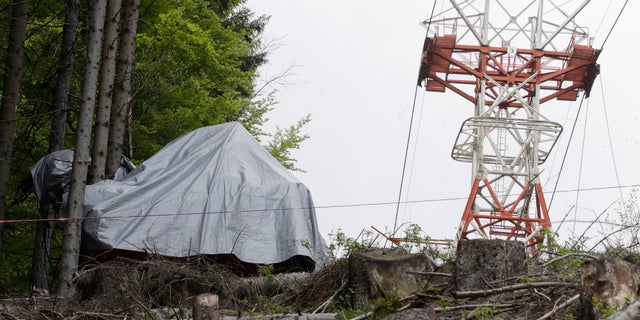 The wreckage of a cable car after it collapsed near the summit of the Stresa-Mottarone line in the Piedmont region, northern Italy, Wednesday, May 26, 2021. Police have made three arrests in the cable car disaster that killed 14 people after an investigation showed a clamp, placed on the brake as a patchwork repair effort, prevented the brake from engaging after the lead cable snapped. (AP Photo/Luca Bruno)