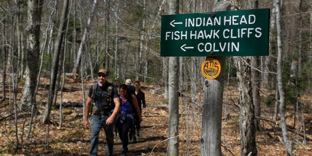 Hikers walk along the trail from Indian Head summit inside the Adirondack Mountain Reserve, Saturday, May 15, 2021, near St. Huberts, N.Y. A free reservation system went online recently to control the growing number of visitors packing the parking lot and tramping on the trails through the private land of the Adirondack Mountain Reserve. The increasingly common requirements, in effect from Maui to Maine, offer a trade-off to visitors, sacrificing spontaneity and ease of access for benefits like guaranteed parking spots and more elbow room in the woods. (AP Photo/Julie Jacobson)