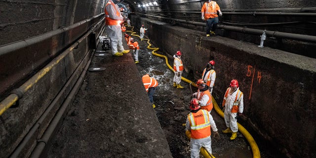 FILE - In this March 20, 2021 file photo, Amtrak workers perform tunnel repairs to a partially flooded train track bed, in Weehawken, N.J. (AP Photo/John Minchillo, File)