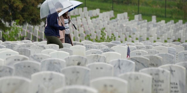 Woman carries umbrella while in cemetery on Memorial Day