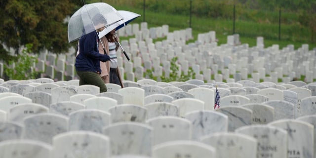 Woman carries umbrella while in cemetery on Memorial Day