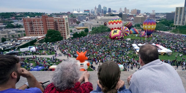 People watch hot air balloons during a balloon glow as part of Memorial Day weekend activities on the grounds of the National World War I Museum and Memorial Sunday, May 30, 2021, in Kansas City, Mo. (AP Photo/Charlie Riedel)