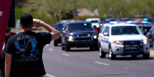 People line the streets as the body of Chandler Police Officer Christopher Farrar, killed in the line of duty last Thursday, is escorted during a large multi-jurisdiction police procession Friday, May 7, 2021, in Chandler, Ariz. Officer Farrar was struck by a suspect in a stolen vehicle after a long police chase. (AP Photo/Ross D. Franklin)