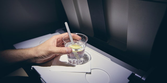 person drinking alcohol on plane