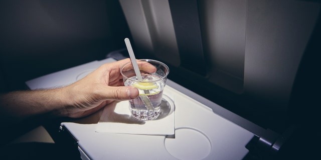 person drinking alcohol on plane