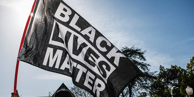 LOS ANGELES, CALIFORNIA, UNITED STATES - 2021/04/20: A protester waves a Black Lives Matter flag during the demonstration. Hours after the verdict of the Derek Chauvin trial, protesters meet outside of Los Angeles Mayor Eric Garcetti's home to protest his proposed funding of the Los Angeles Police Department.