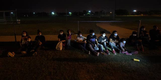 Migrants wait at an intake area after turning themselves in upon crossing the U.S.-Mexico border, late Tuesday, May 11, 2021, in La Joya, Texas. The U.S. government continues to report large numbers of migrants crossing the U.S.-Mexico border with an increase in adult crossers. But families and unaccompanied children are still arriving in dramatic numbers despite the weather changing in the Rio Grande Valley registering hotter days and nights. (AP Photo/Gregory Bull)