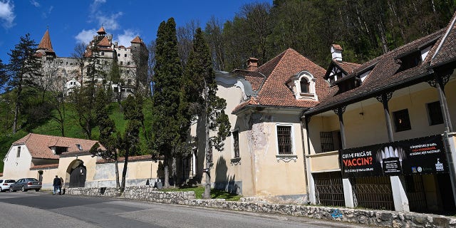 Ein Zeichen in rumänischer Sprache geschrieben "Wer hat Angst vor dem Impfstoff" Spritzen werden als Reißzähne von Vampiren dargestellt, die einen Impfmarathon ankündigen, der in organisiert wurde "Kleie Schloss" (Hintergrund) im Dorf Bran, 8. Mai 2021 (Foto von Daniel Mihaelescu / AFP) (Foto von Daniel Mihaelescu / AFP über Getty Images)