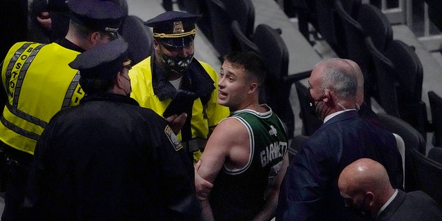 A fan is handcuffed and escorted out of TD Garden by police after allegedly throwing a water bottle at Brooklyn Nets' Kyrie Irving as Irving left the court after Game 4 of an NBA first-round playoff series, Sunday, May 30, 2021, in Boston. The Nets won 141-126. (AP Photo/Elise Amendola)