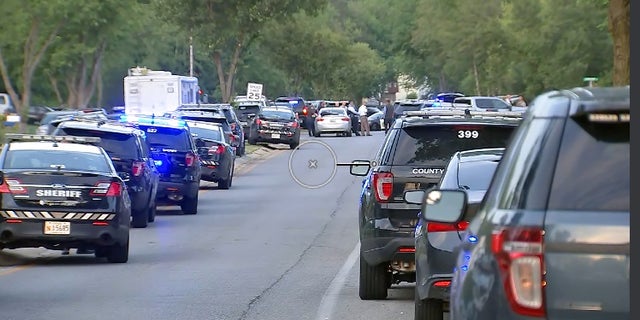 Charles County Sheriff's vehicles on a street near where two officers were shot Monday. The alleged gunman has barricaded himself inside a home, authorities said.