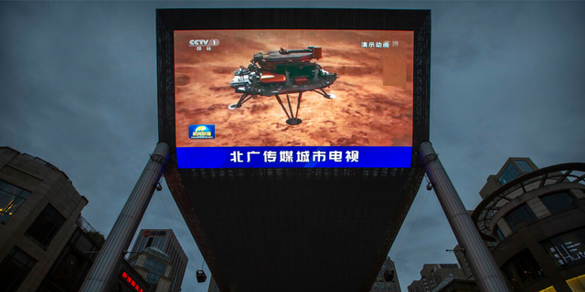 A Chinese state media broadcast of a news report about the country's successful landing of a probe on Mars is shown on a large video screen at a shopping mall in Beijing, Saturday, May 15, 2021.  