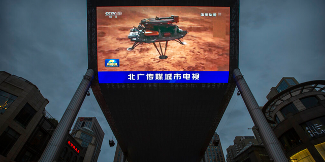 A Chinese state media broadcast of a news report about the country's successful landing of a probe on Mars is shown on a large video screen at a shopping mall in Beijing, Saturday, May 15, 2021.  