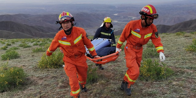 Rescuers carrying equipment as they search for runners who were competing in a 100-kilometre cross-country mountain race when extreme weather hit the area, leaving at least 20 dead, near the city of Baiyin in China's northwestern Gansu province.