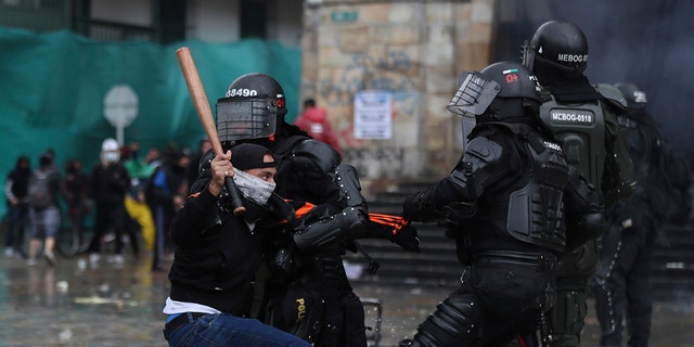 A protester clashes with the police during an anti-government protest in Bogota, Colombia, Wednesday, May 5, 2021. The protests that began last week over a tax reform proposal continue despite President Ivan Duque's withdrawal of the tax plan on Sunday, May 2. (AP Photo/Fernando Vergara)