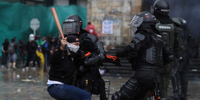 A protester clashes with the police during an anti-government protest in Bogota, Colombia, Wednesday, May 5, 2021. The protests that began last week over a tax reform proposal continue despite President Ivan Duque's withdrawal of the tax plan on Sunday, May 2. (AP Photo/Fernando Vergara)