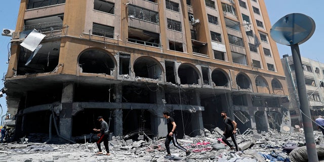 La gente inspecciona los escombros de un edificio dañado que fue alcanzado por un ataque aéreo israelí en la ciudad de Gaza el miércoles.  (AP)