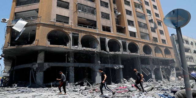 La gente inspecciona los escombros de un edificio dañado que fue alcanzado por un ataque aéreo israelí en la ciudad de Gaza el miércoles.  (AP)