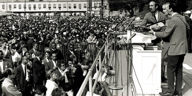 American folk and pop group Peter, Paul and Mary perform during the March on Washington for Jobs and Freedom, Washington DC, August 28, 1963. The trio behind the microphone features, from left, Paul Stookey, Mary Travers (1936 - 2009), and Peter Yarrow. The march and rally provided the setting for the Reverend Martin Luther King Jr's iconic 'I Have a Dream' speech.
