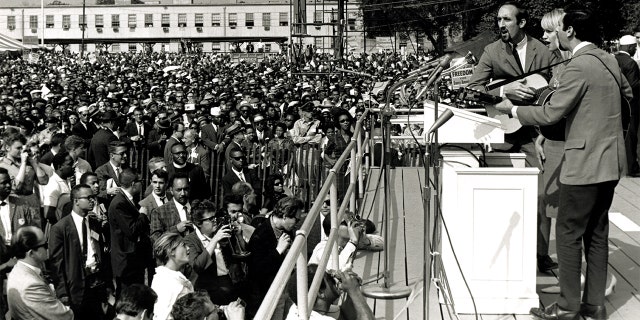 American folk and pop group Peter, Paul and Mary perform during the March on Washington for Jobs and Freedom, Washington DC, August 28, 1963. The trio behind the microphone features, from left, Paul Stookey, Mary Travers (1936 - 2009), and Peter Yarrow. The march and rally provided the setting for the Reverend Martin Luther King Jr's iconic 'I Have a Dream' speech. 